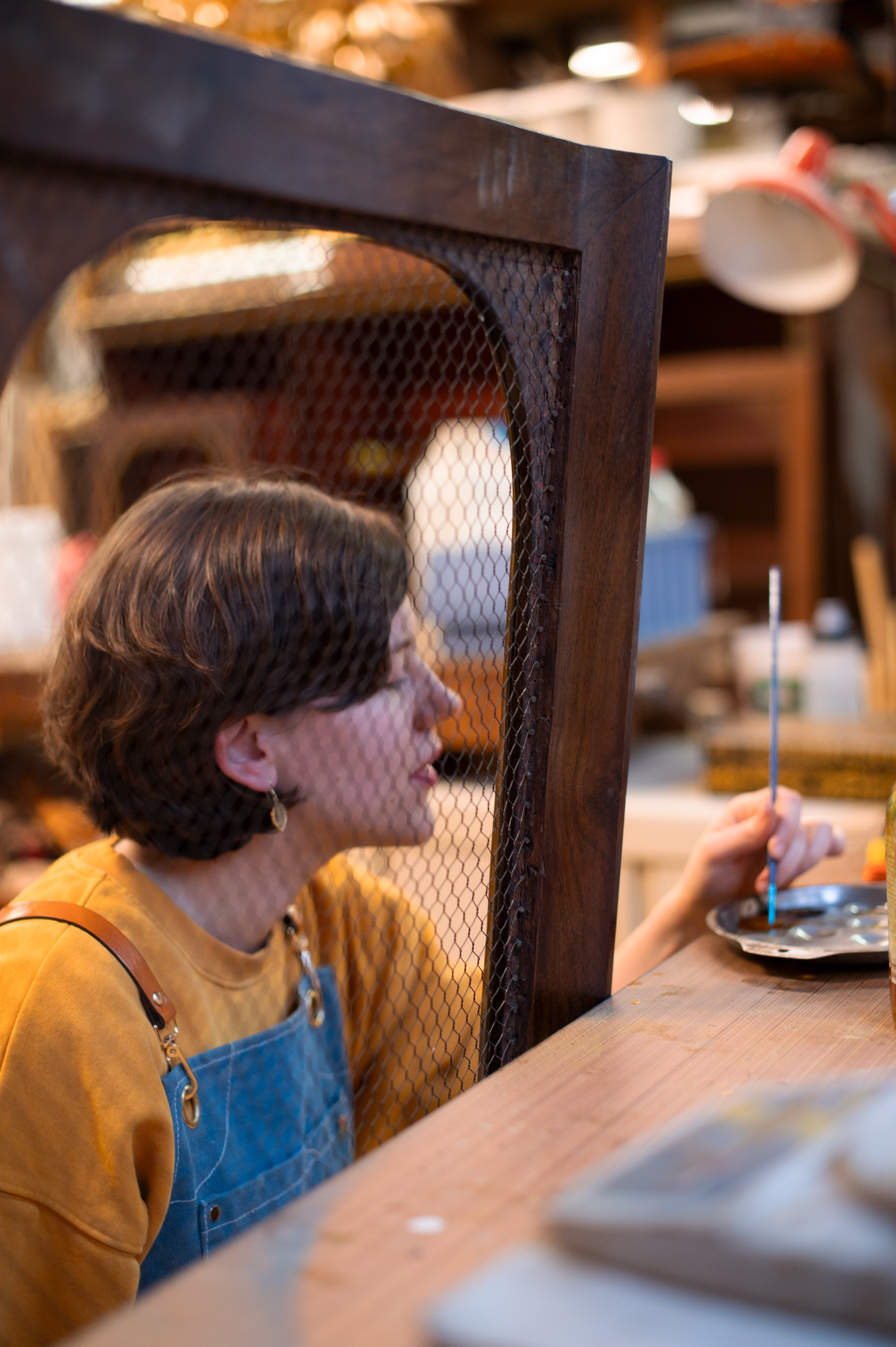 Restauratrice à l'atelier, examinant un cadre en bois ancien